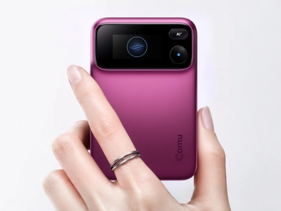 Image of a hand holding a magenta-colored compact Comu AI device