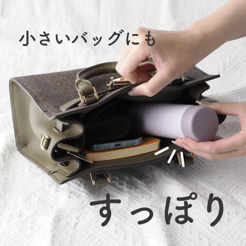 A mini bottle, smartphone, and book stored in a small handbag