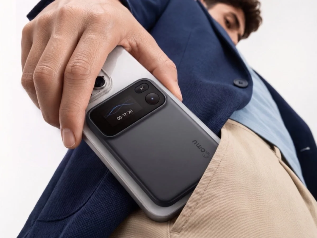 Image of a person holding a smartphone with the Comu AI device attached, partially in a pocket