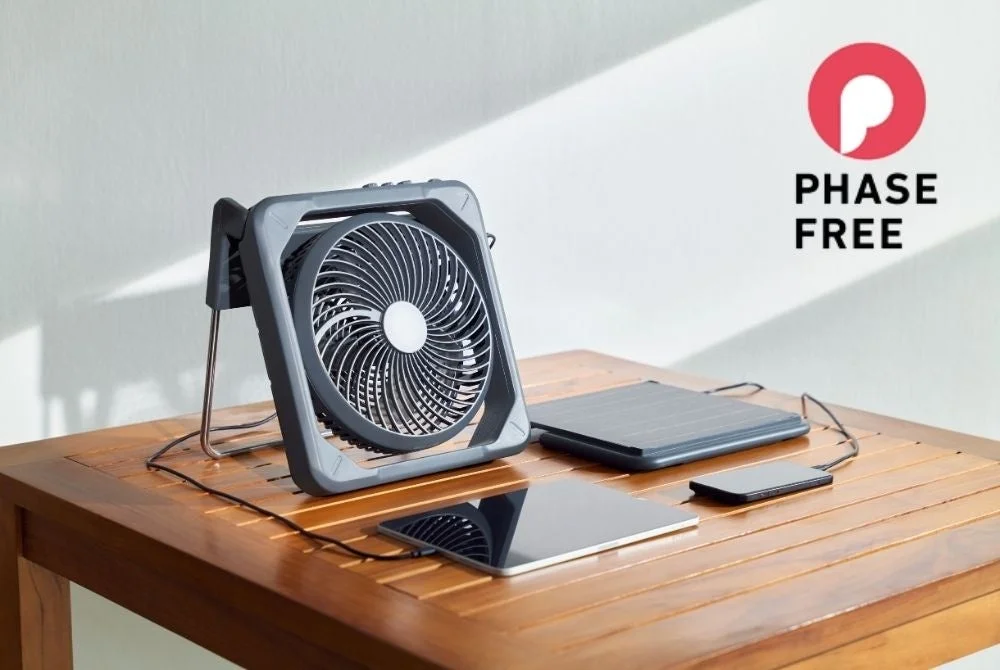 Portable fan, solar panel, tablet, and smartphone on a wooden table