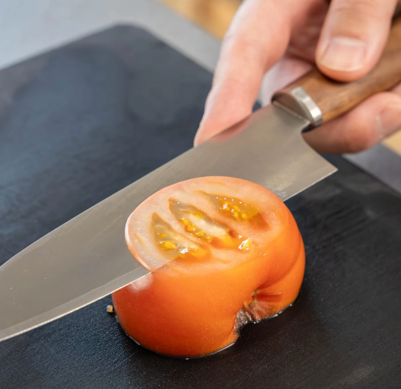 Image of a hand slicing a tomato with a knife