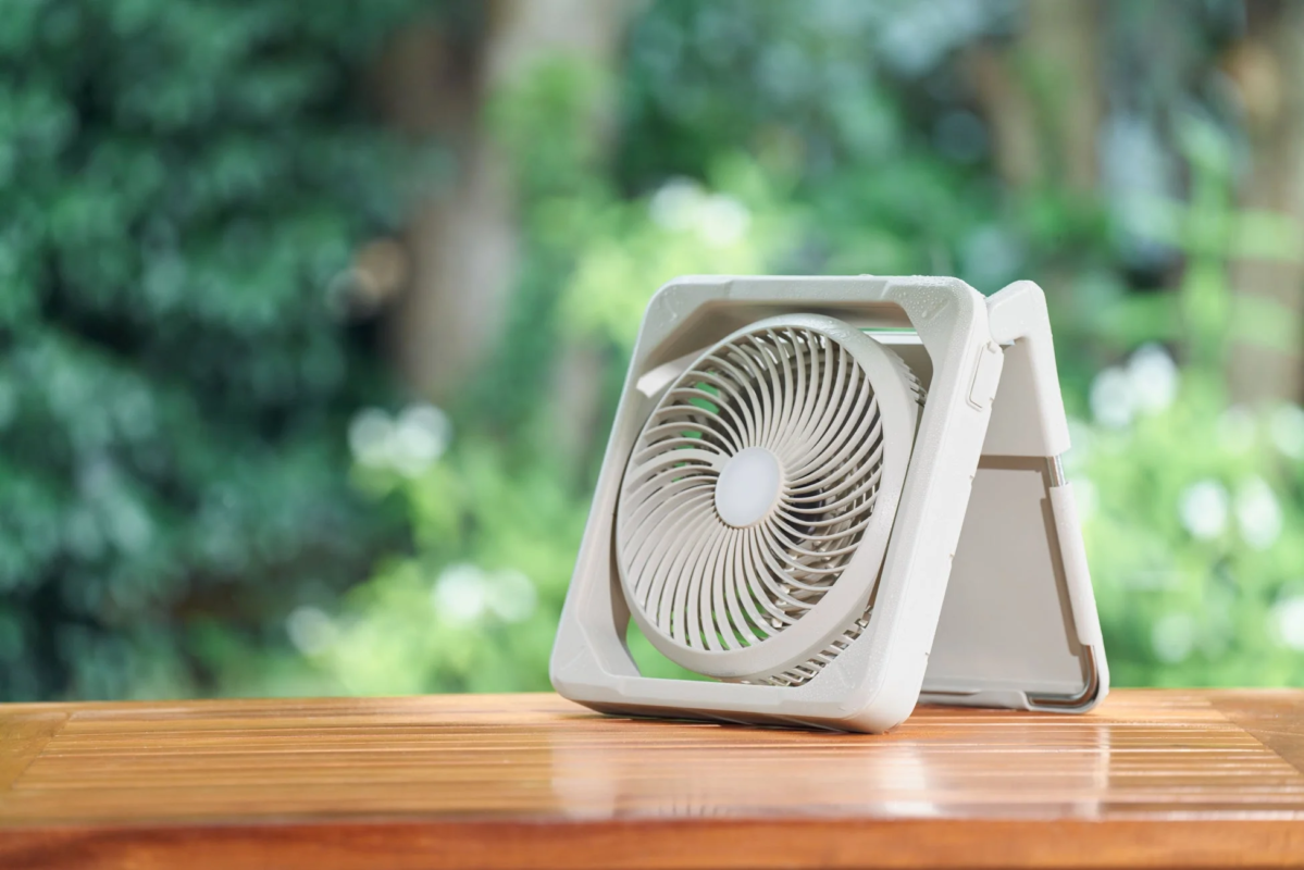 Portable fan on a wooden table outdoors