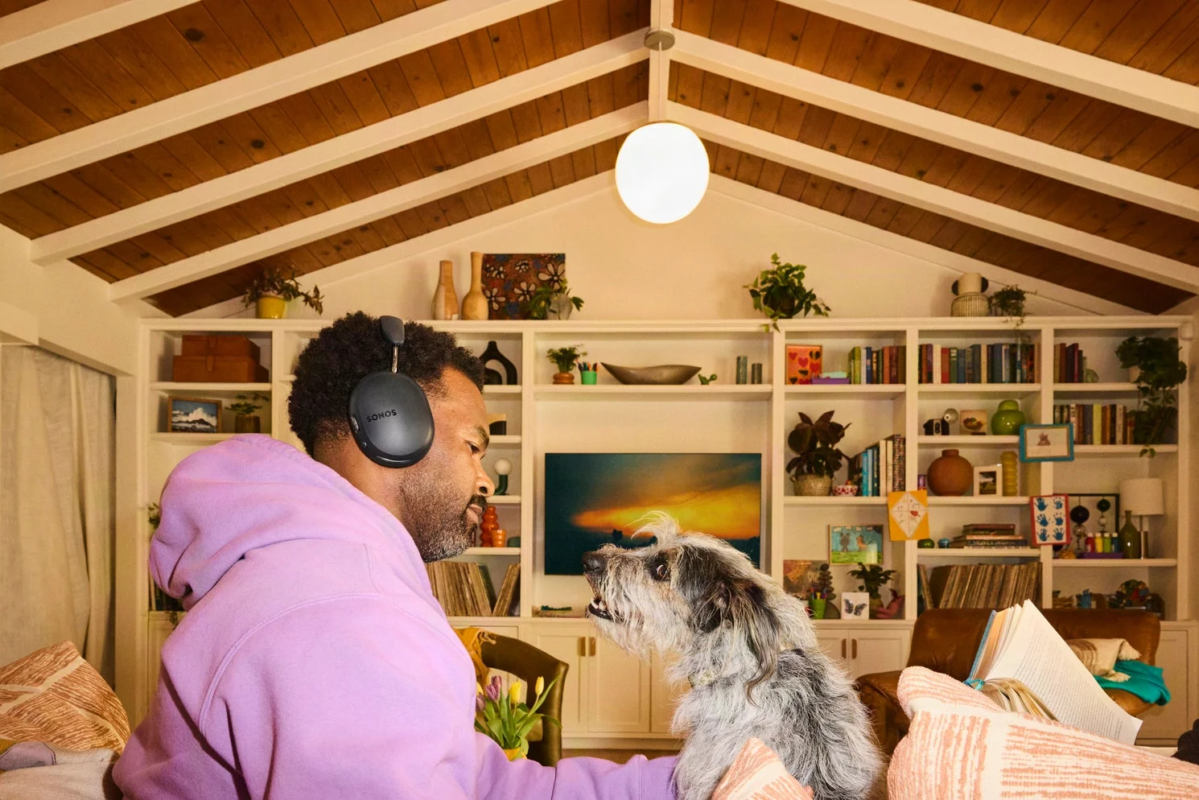 A man wearing headphones interacting with his dog in a living room