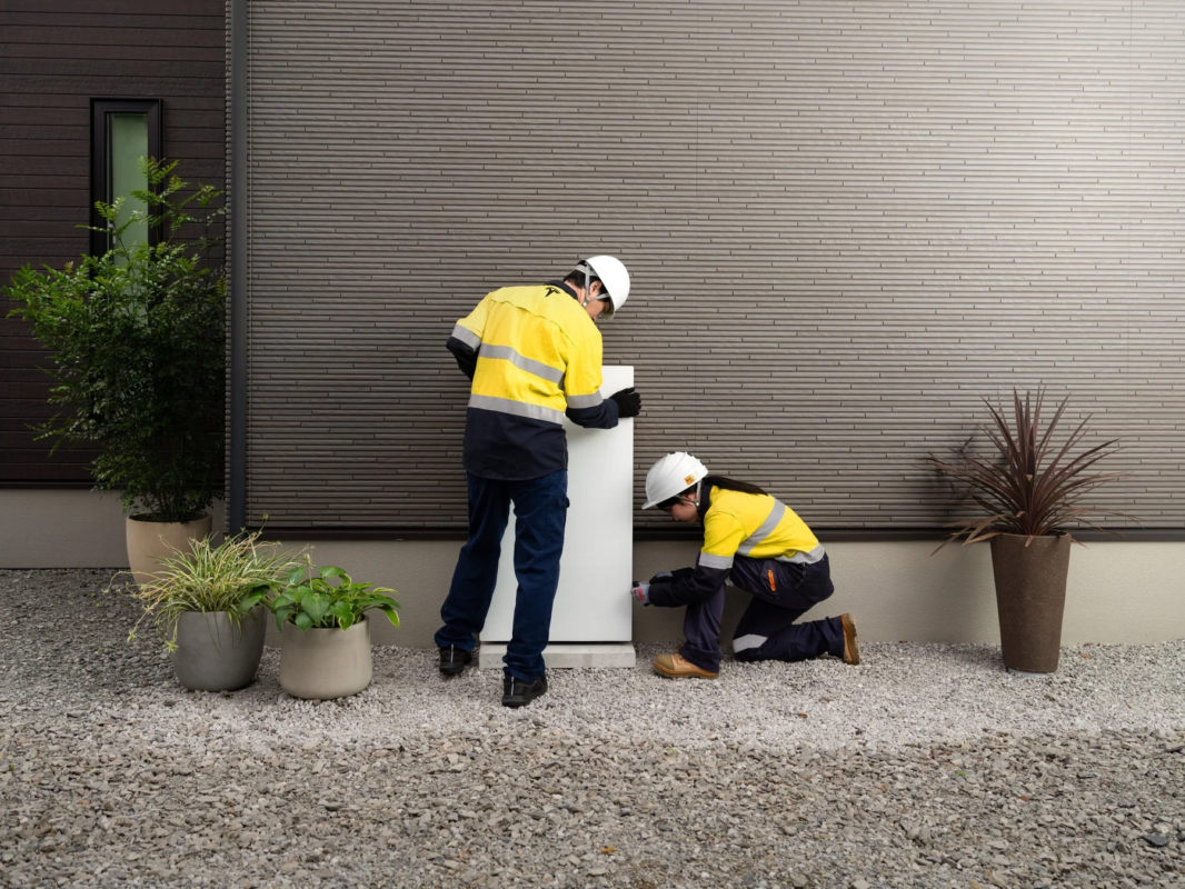 Workers installing a Powerwall unit at a residence